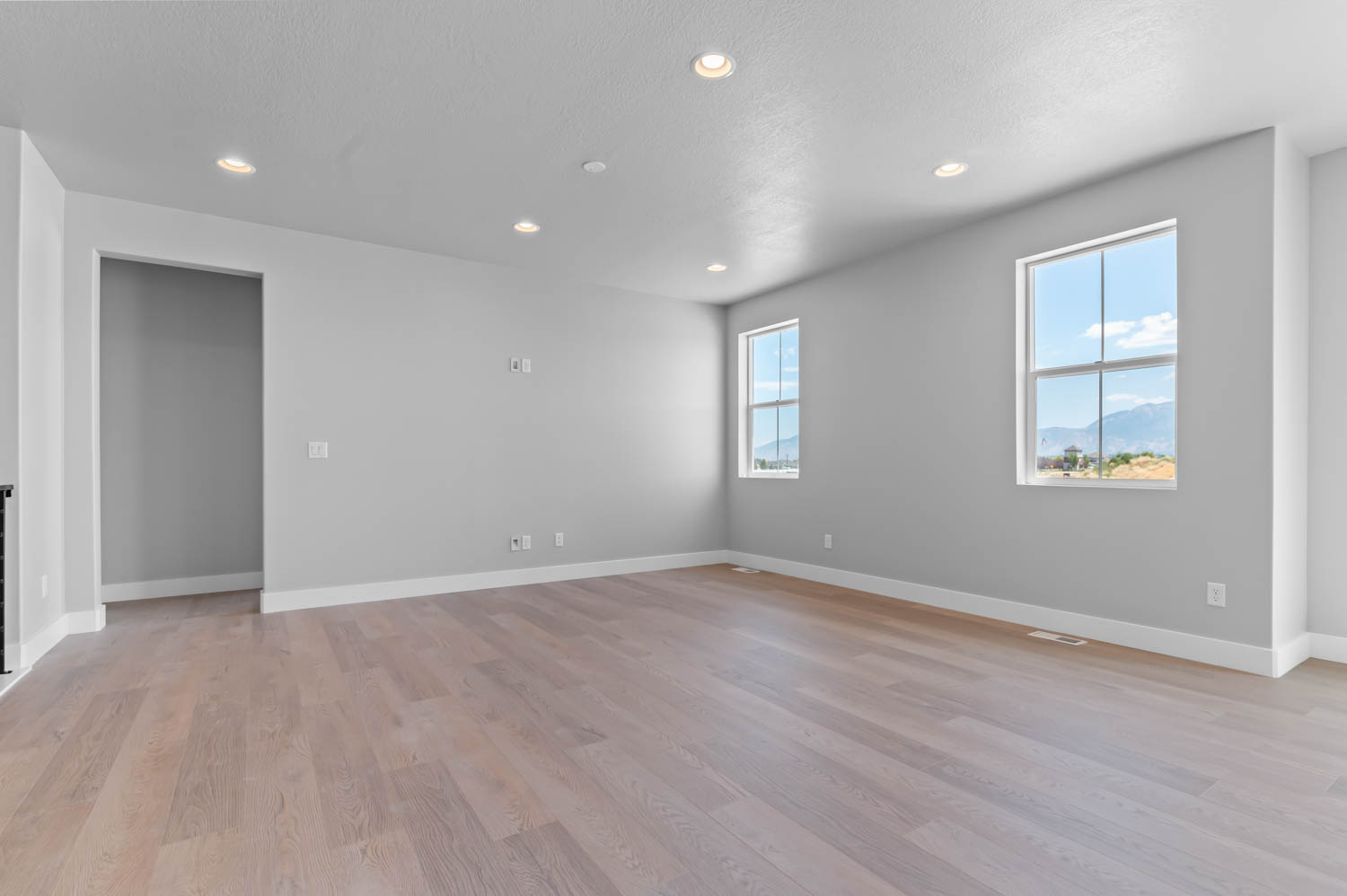 Spacious room featuring wood-finish flooring, recessed lighting, and multiple windows with mountain scenery