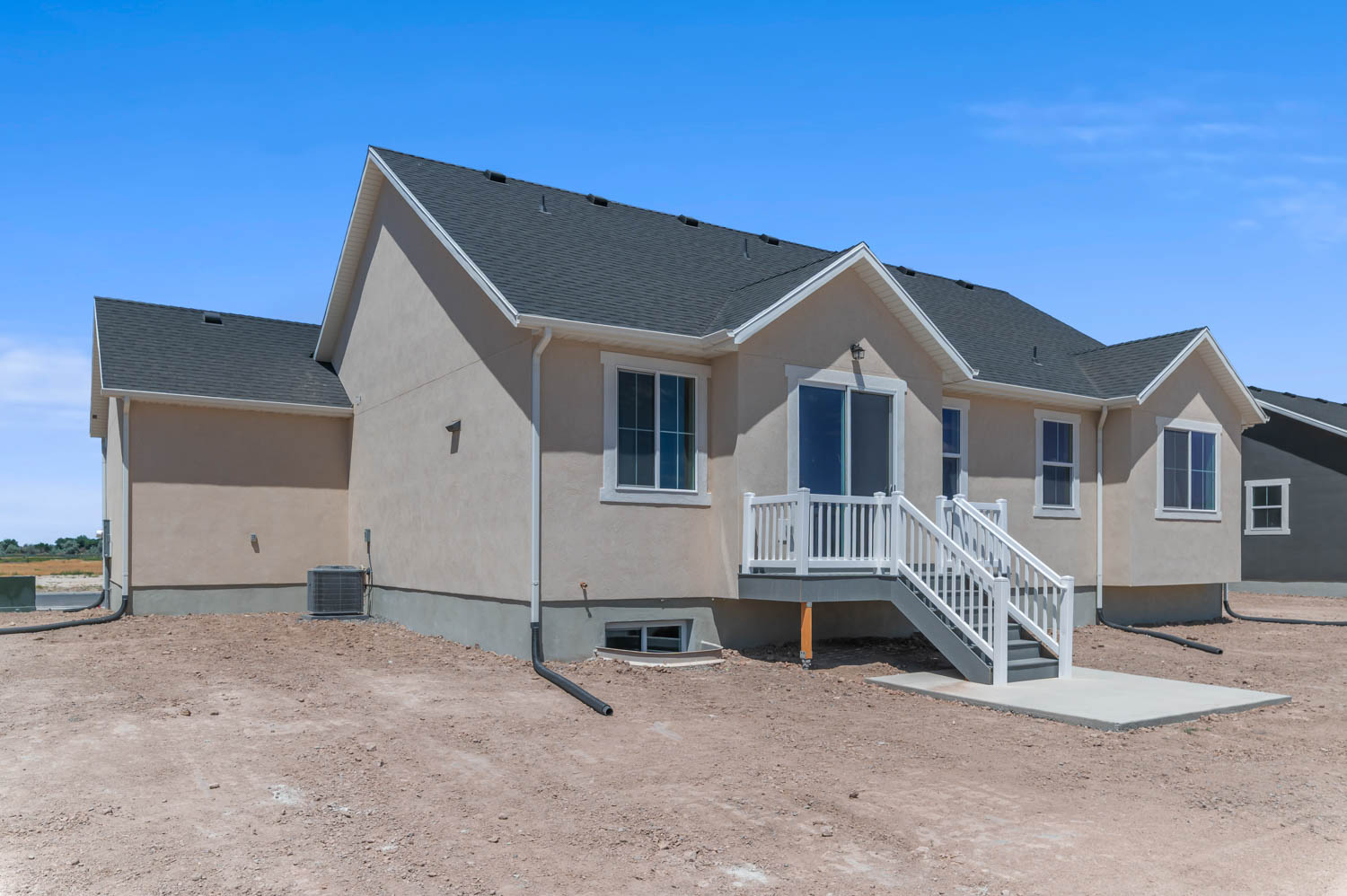 Rear exterior showcasing a neutral stucco finish and a dark shingle roof