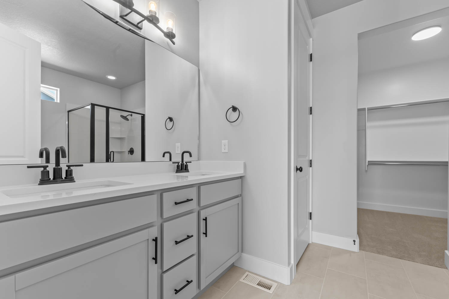 Bathroom with a dual vanity featuring light gray cabinetry, white countertops, and matte black fixtures