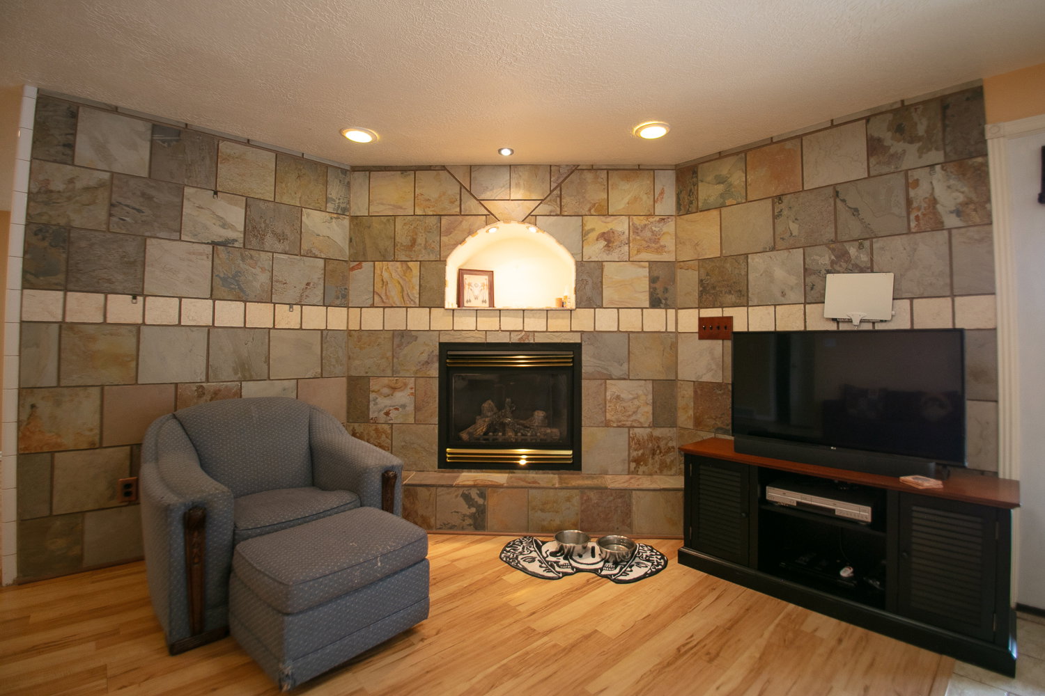 Fireplace featuring a stone tile surround, a built-in arched alcove with recessed lighting, and a hearth