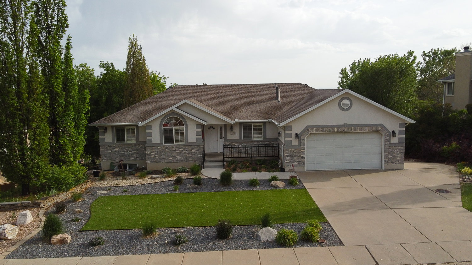 Single-story residence featuring a two-car garage, stone and stucco exterior, and a paved driveway