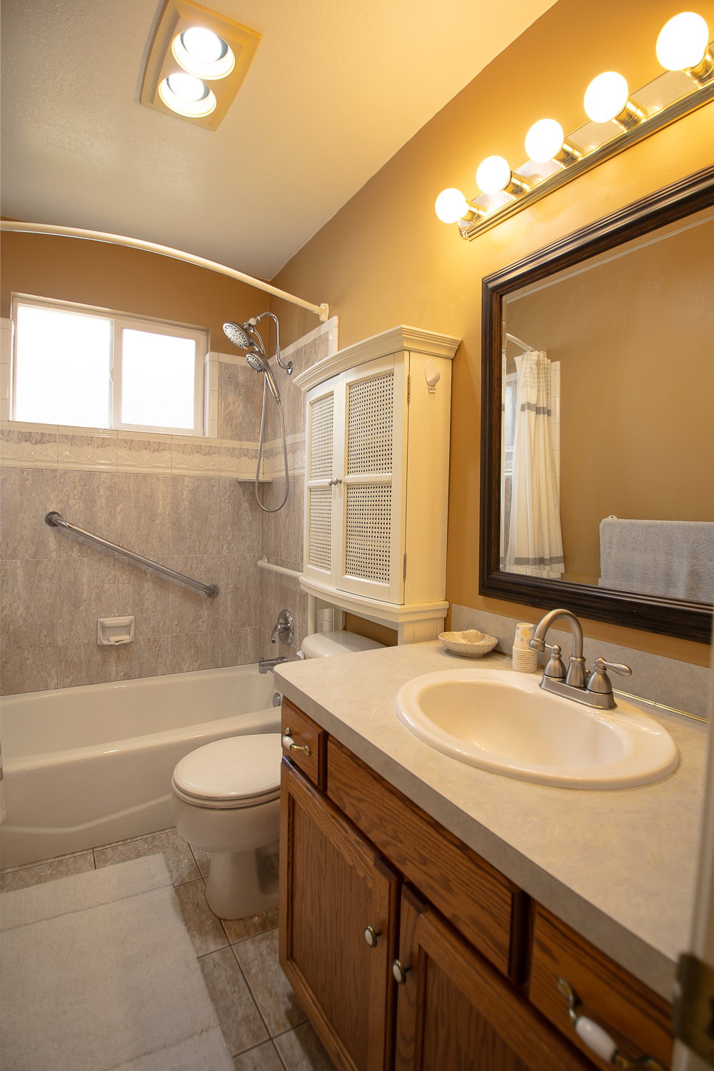 Bathroom featuring a wood-finish vanity with a light-toned countertop and an oval sink