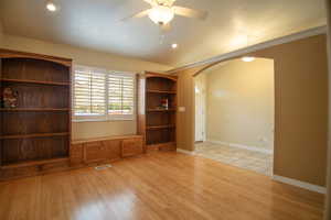 Spacious room featuring wood-finish flooring, recessed lighting, and a ceiling fan