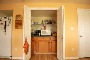 Kitchenette with wood-finish flooring, wood cabinetry, and a countertop with built-in shelving