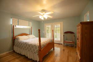 Bedroom featuring natural wood-finish flooring, light blue wall paint, and a ceiling fan with integrated lighting