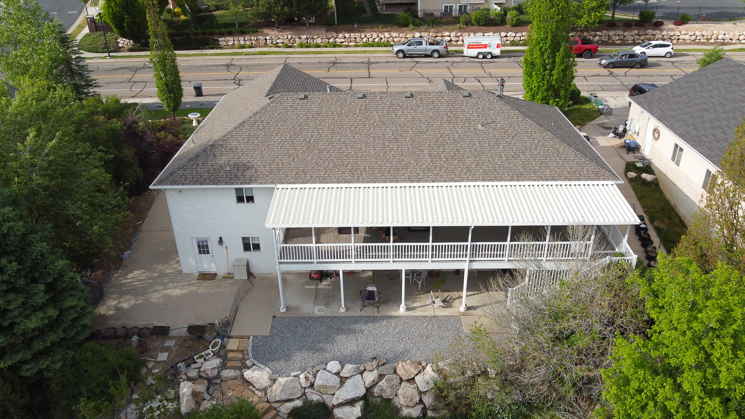 Spacious property featuring a large composite shingle roof, white exterior siding, and a covered upper-level deck with white railings