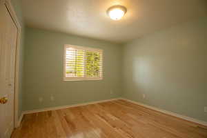 Wood-finish flooring throughout, complemented by a window with white plantation shutters and a bi-fold closet door
