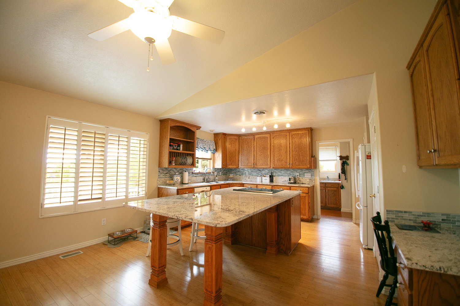 Kitchen featuring wood-finish flooring, a large island with a light-toned countertop, and wood cabinetry