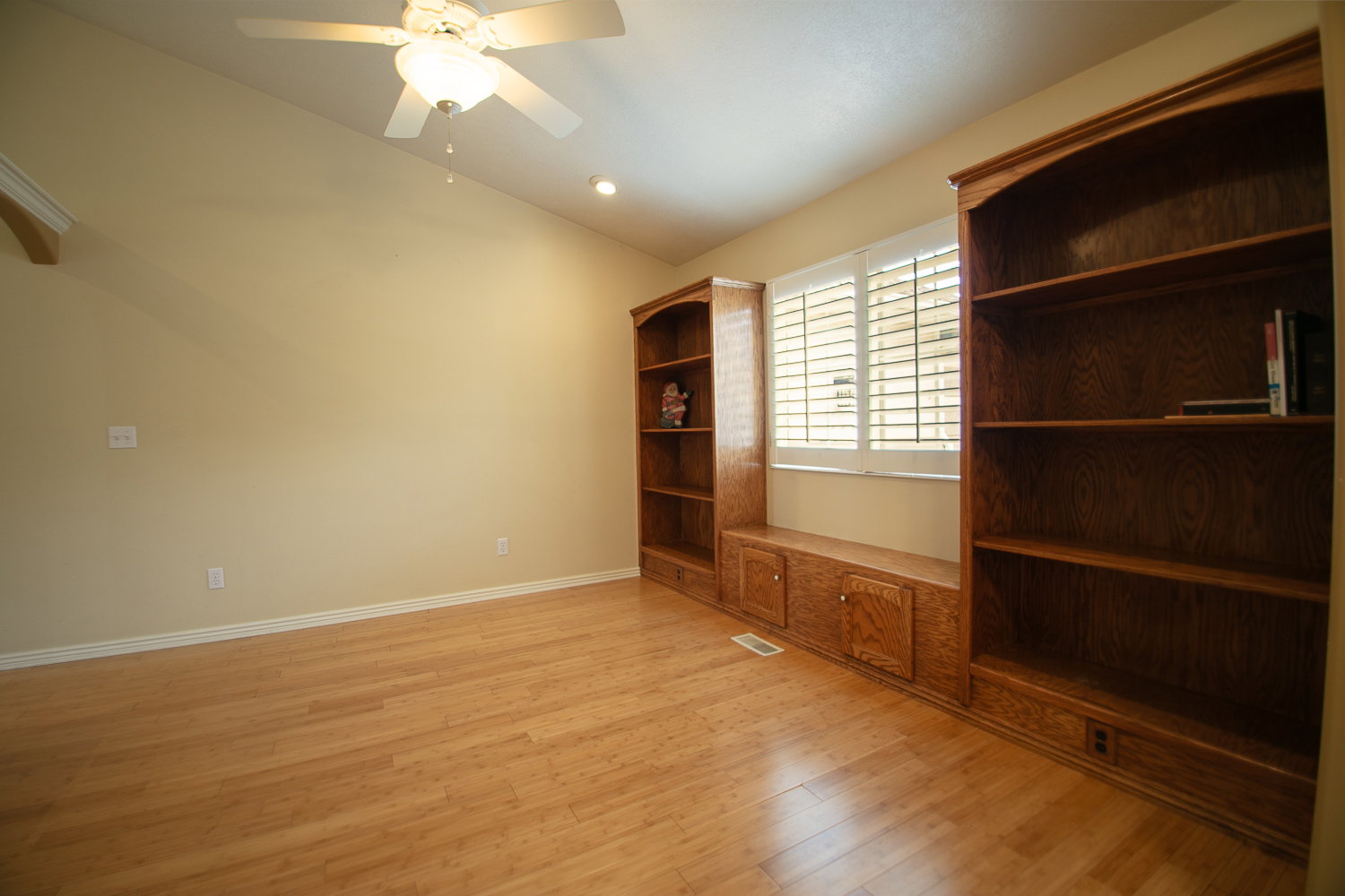 Room with wood-finish flooring, vaulted ceilings, and a ceiling fan