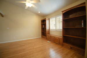 Room with wood-finish flooring, vaulted ceilings, and a ceiling fan