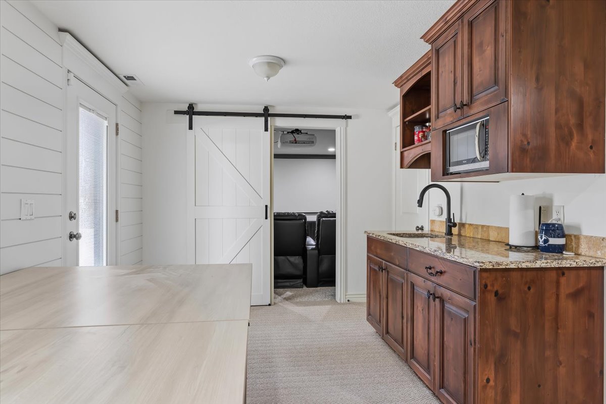 Wet bar featuring rich wood cabinetry, granite countertop, and integrated microwave
