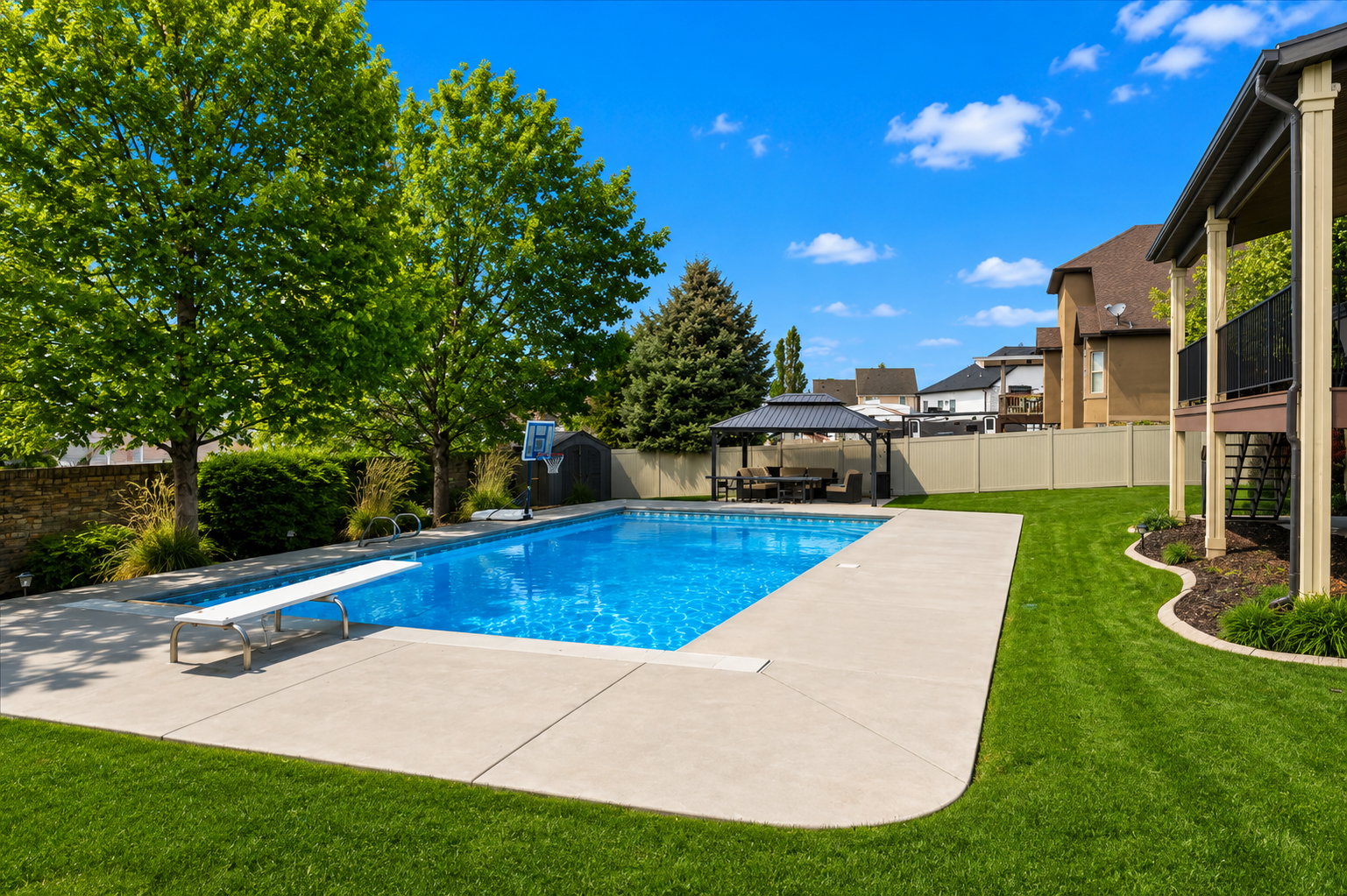 In-ground swimming pool with diving board and expansive concrete surround
