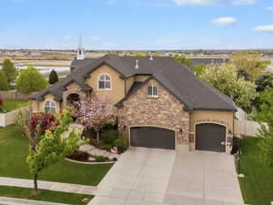 Stately residence featuring a stone and stucco exterior, arched windows, and a multi-car garage with arched doors