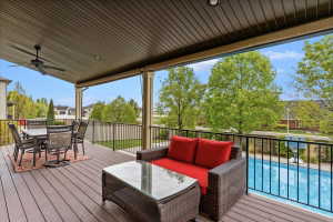 Covered deck with composite decking, featuring a ceiling fan, recessed lighting, and a black wrought iron railing