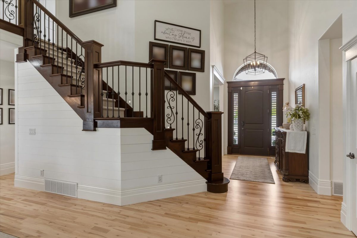 Grand entryway featuring a dark wood front door with sidelights, a transom window, and a geometric chandelier