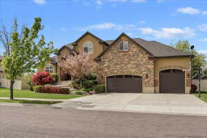 Stucco and stone facade home featuring a multi-car garage, arched entryways, and mature landscaping