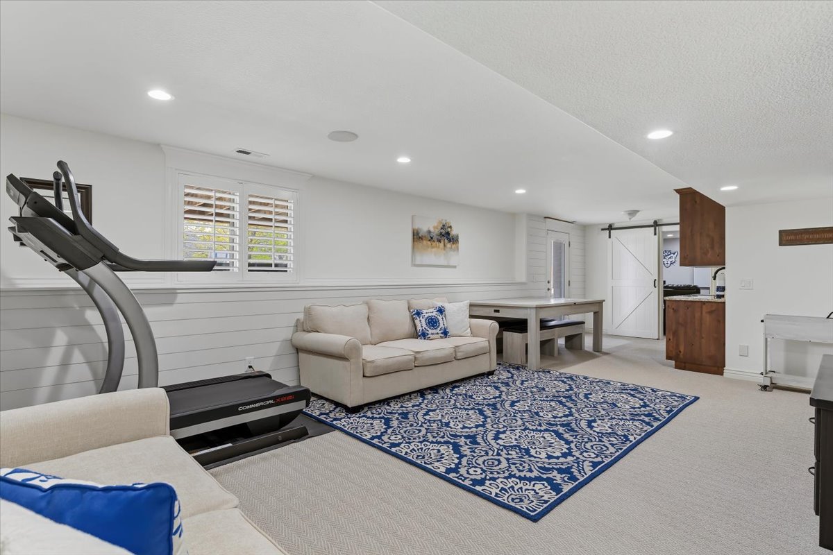 Spacious recreation area featuring recessed lighting, white shiplap wainscoting, and carpet flooring