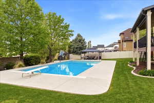 In-ground swimming pool with diving board, surrounded by concrete decking