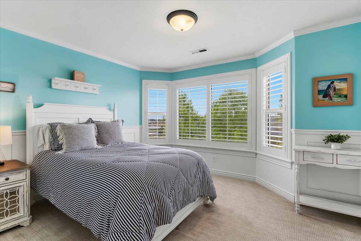 Room featuring a bay window with plantation shutters, crown molding, two-tone wall treatment with wainscoting, and a semi-flush mount ceiling light