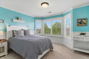Room featuring a bay window with plantation shutters, crown molding, two-tone wall treatment with wainscoting, and a semi-flush mount ceiling light