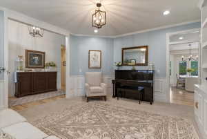 Open living area featuring light blue walls with wainscoting, recessed lighting, and a decorative ceiling fixture