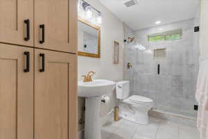 Full bathroom featuring a walk-in shower with marble-style tile surround, integrated niche, and a glass enclosure
