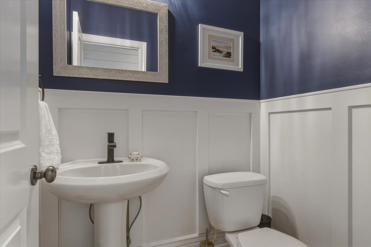 Pedestal sink with dark bronze faucet, framed mirror, and board and batten wainscoting