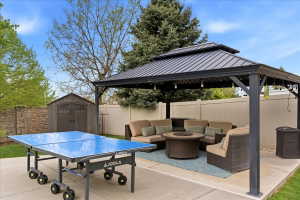 Expansive concrete patio featuring a permanent gazebo with a metal roof, an outdoor storage shed, and a privacy fence