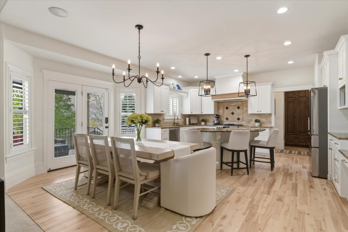 Open-concept kitchen and dining area featuring light wood-finish flooring, white cabinetry, and granite countertops