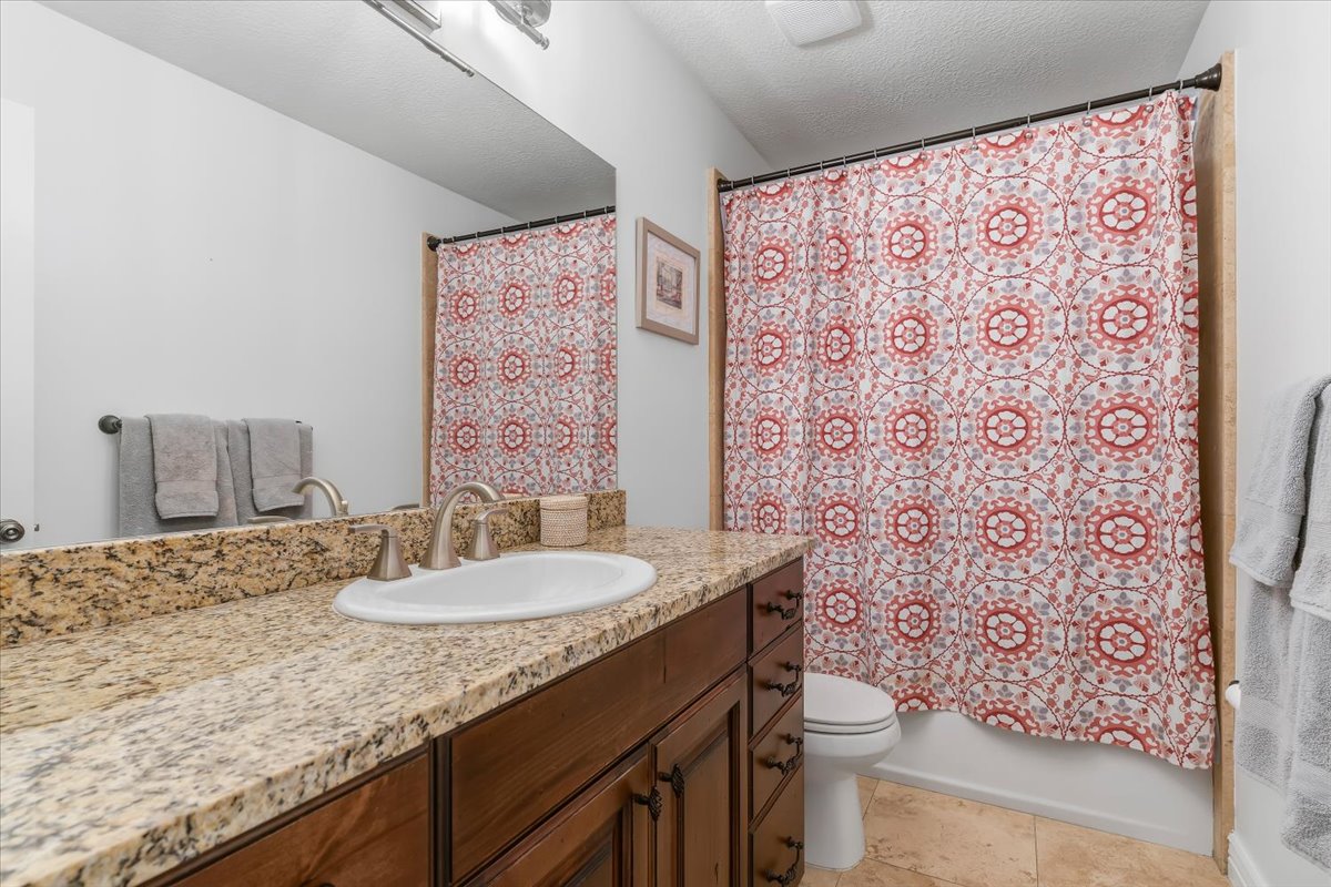 Bathroom featuring a single-sink vanity with a granite countertop, wood-finish cabinetry, and a brushed nickel faucet