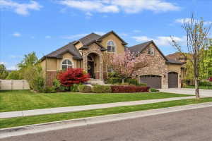 Stucco and stone exterior featuring an arched entryway, multiple gables, and an attached two-car garage