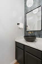 Contemporary bathroom featuring a black vanity with a white countertop and a vessel sink