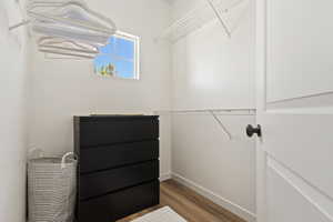 Walk-in closet with grid shelving, wood-finish flooring, and a white interior door with a black knob
