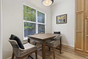 Dining area featuring a large window with blinds, wood-finish flooring, and built-in wood cabinetry