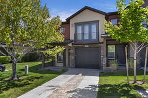 Contemporary townhome exterior featuring an integrated garage, a second-story balcony with French doors, and a covered entry