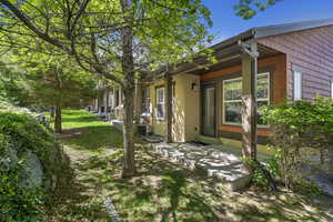 Rear exterior featuring a covered patio, vertical wood columns, shingle-style siding, and a private entry door with an exterior light fixture