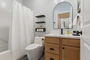 Bathroom featuring a light wood-finish vanity with a white countertop and integrated sink, matte black hardware, and an arched mirror