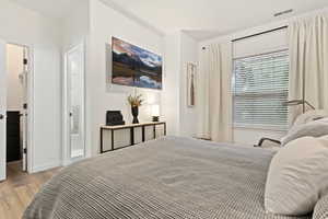 Interior room featuring wood-finish flooring, white walls, and a window with blinds and drapes