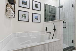 Built-in soaking tub with matte black fixtures, surrounded by white vertical tile