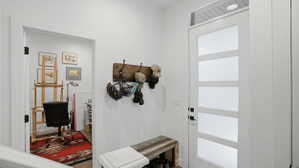 Entryway featuring a modern door with obscured glass panels and transom window, a built-in reclaimed wood bench, and a coat rack with dark metal hooks