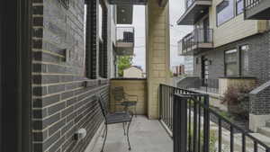 Private exterior patio area featuring dark brick facade, black metal railings, and a concrete surface
