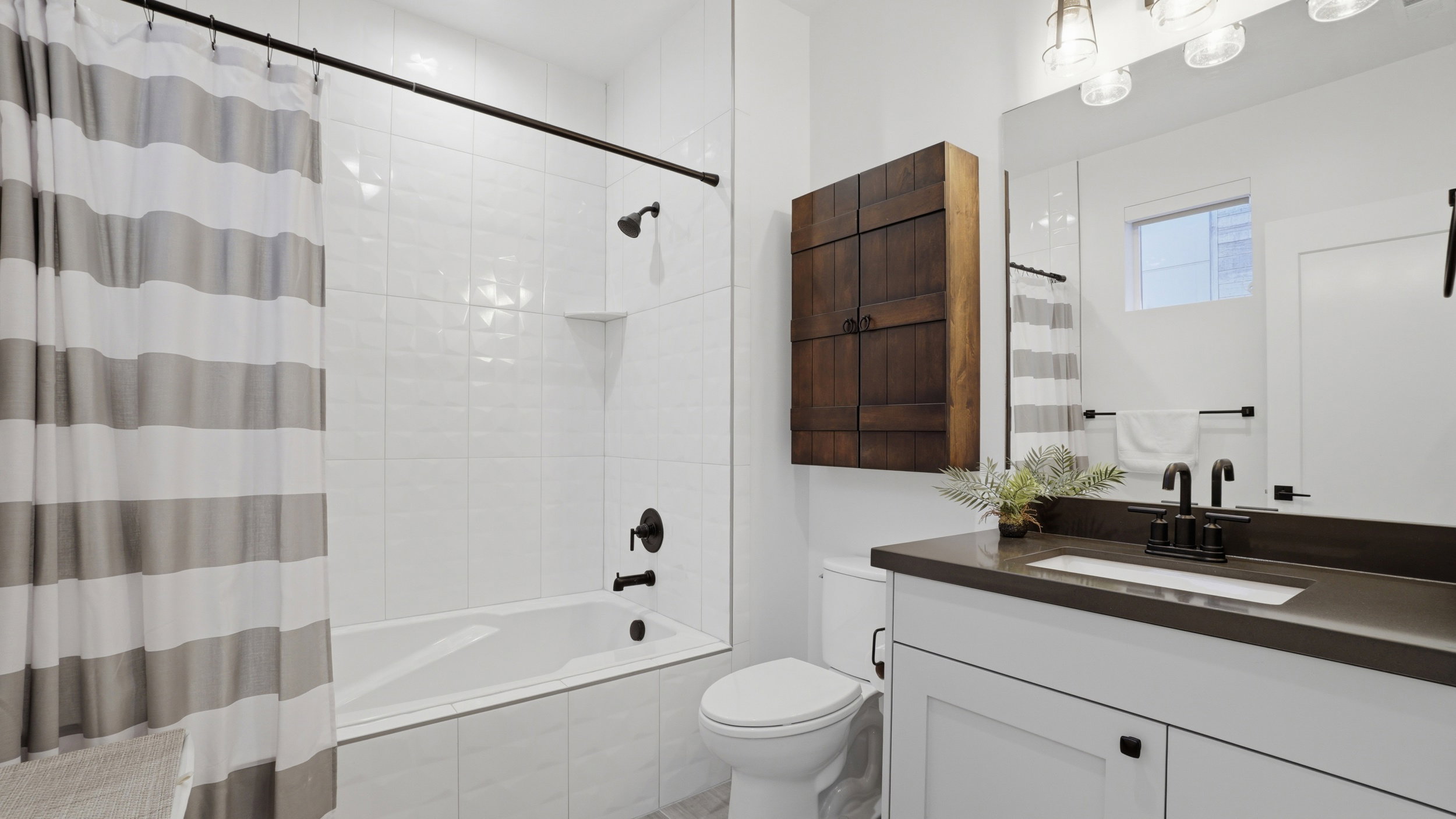 Contemporary bathroom featuring a white vanity with dark countertop, large mirror, and black matte fixtures