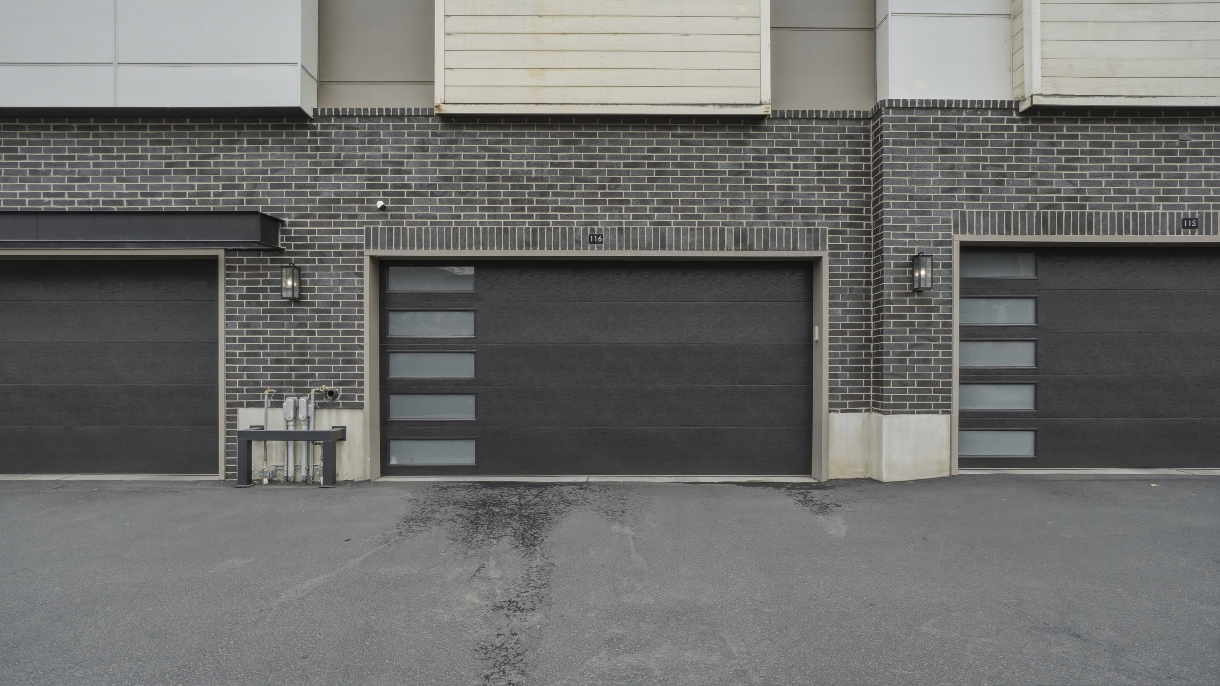 Modern garage doors set against a dark brick facade