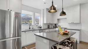 Spacious kitchen featuring white shaker cabinetry, dark countertops, a stainless steel refrigerator, and a tiled backsplash