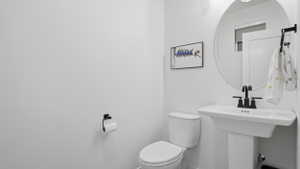 Pedestal sink with matte black faucet, wall-mounted circular mirror, and recessed lighting