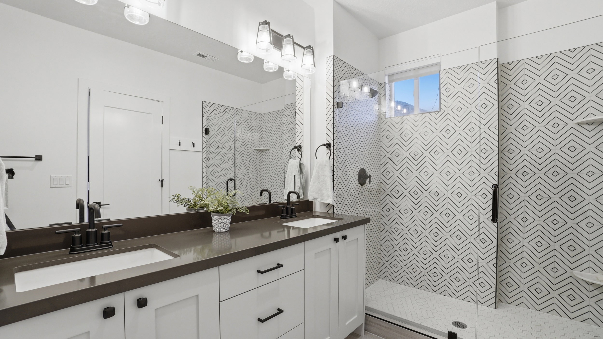 Dual vanity with a dark countertop and undermount sinks, featuring matte black fixtures and hardware
