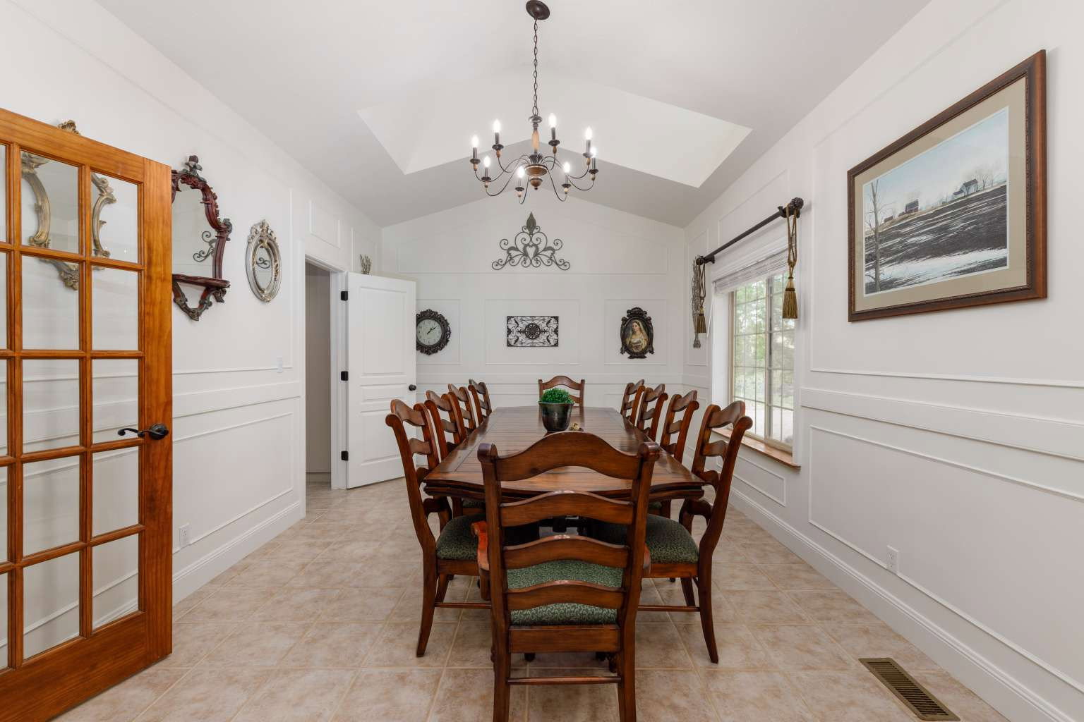 Vaulted ceiling featuring a chandelier, panel molding, wood-finish flooring, a French pane door, and a window with wood trim