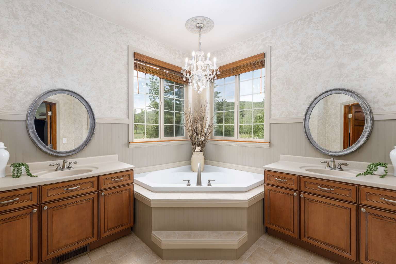Corner soaking tub with dual vanities featuring wood cabinetry and light-toned countertops
