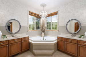 Corner soaking tub with dual vanities featuring wood cabinetry and light-toned countertops