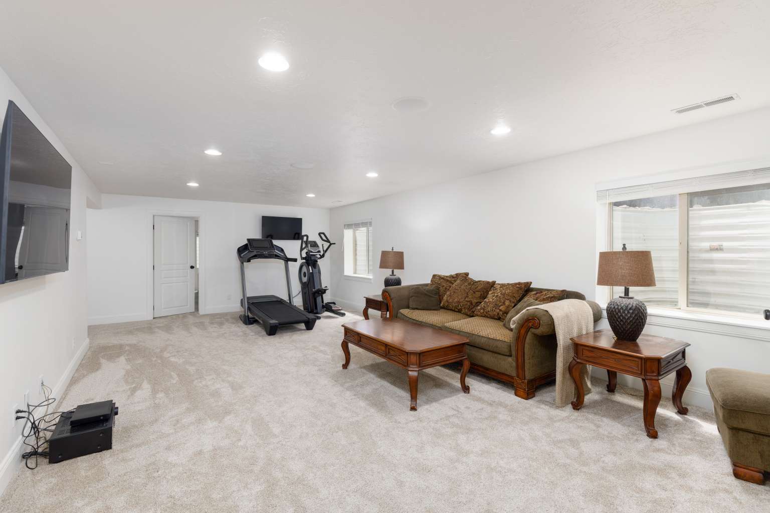 Spacious room featuring light-toned carpet flooring, recessed lighting, and white painted walls